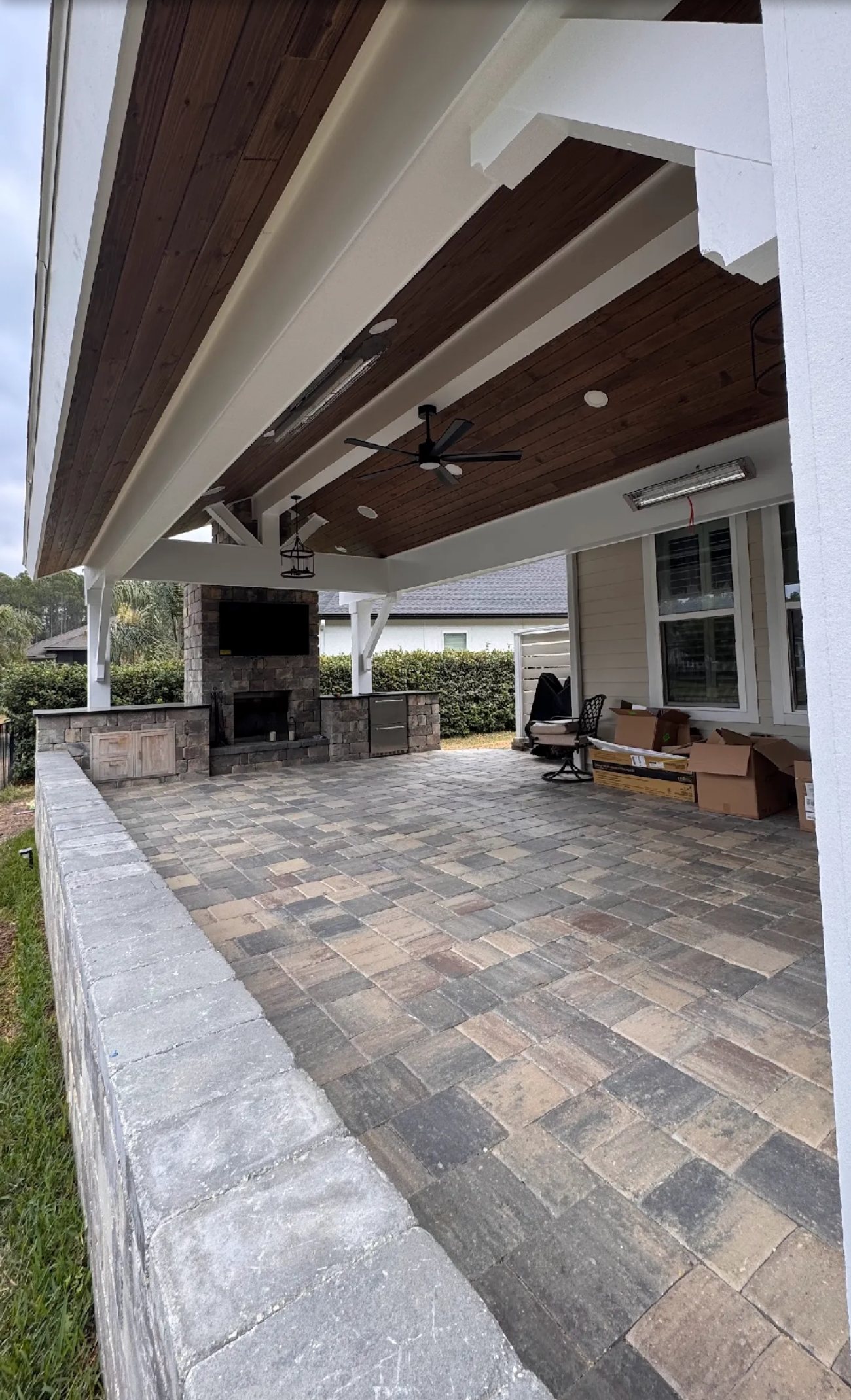 Custom covered patio with fireplace, pavers and seat wall, plus ceiling fans, lighting, a heater and audio