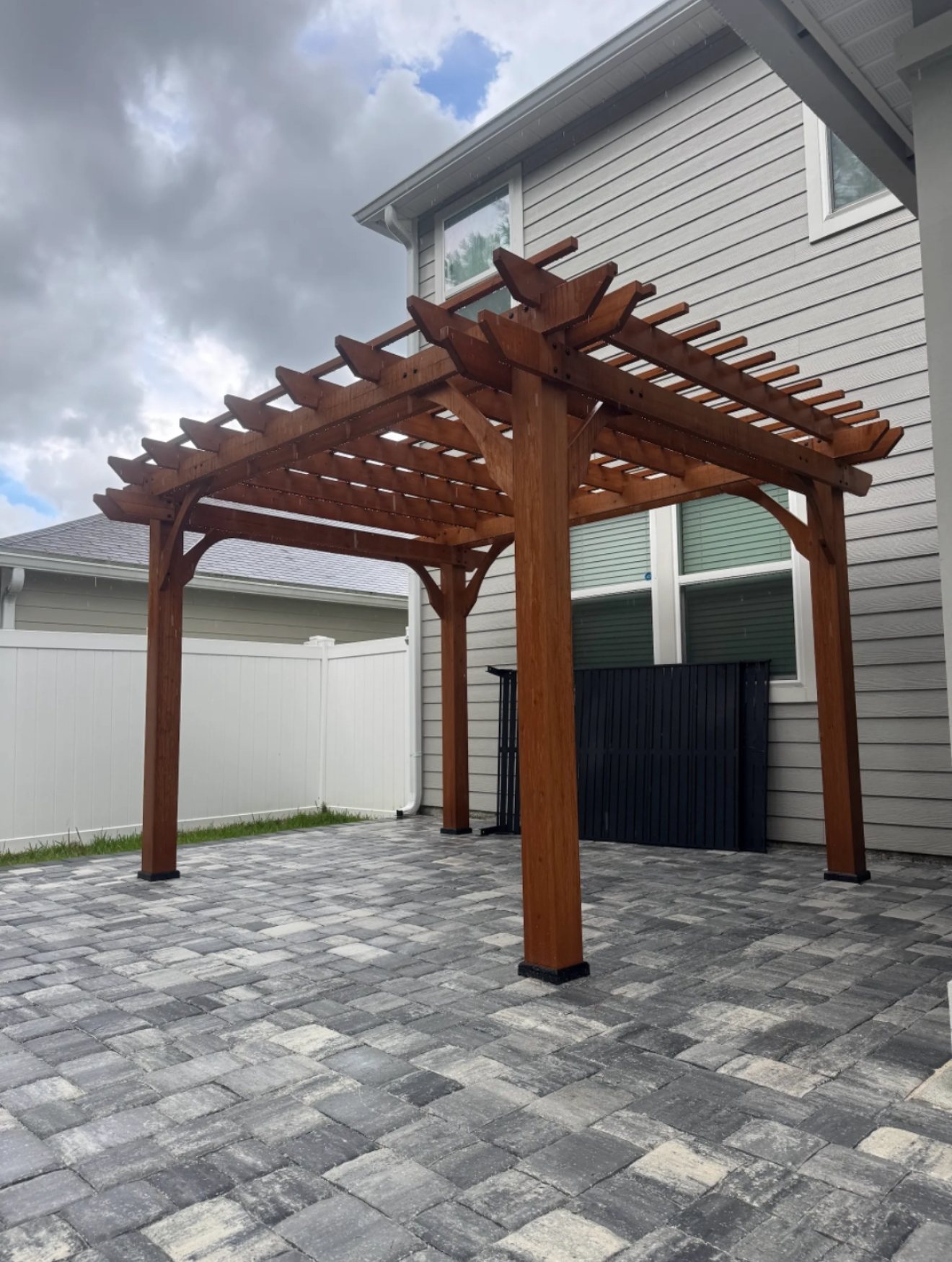 Stained pergola on a paver patio